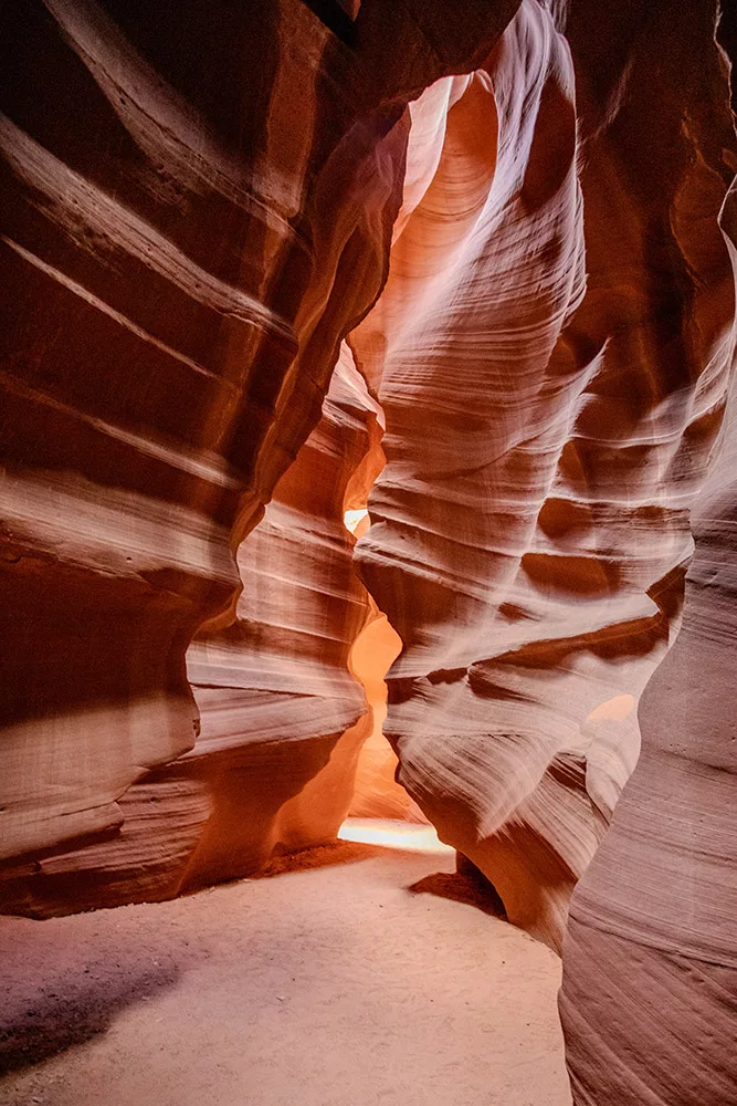 Photographie artistique de l'Upper Antelope Canyon en Arizona montrant les parois de grès sculptées par l'érosion avec des rayons de lumière filtrant à travers les fissures, créant des nuances orange et rouges, tirage d'art limité