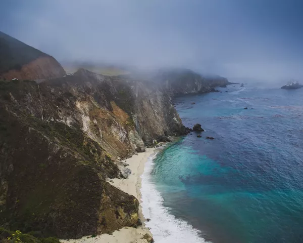 Photographie Big Sur - Californie Photographie artistique des falaises escarpées de Big Sur en Californie avec plage isolée et eaux turquoise de l'océan Pacifique sous un ciel brumeux, tirage d'art paysage marin