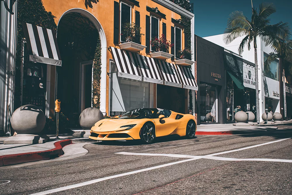 Photographie artistique d'une Ferrari F488 Spider jaune stationnée sur Rodeo Drive à Los Angeles devant des boutiques de luxe, sous le soleil californien, tirage d'art automobile limité