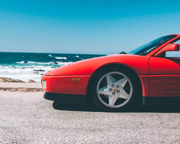 Photographie Ferrari Testa Rossa Spider Photographie artistique d'une Ferrari Testarossa Spider rouge stationnée au bord de l'océan Pacifique en Californie, avec vagues et rochers en arrière-plan sous un ciel bleu azur, tirage d'art automobile limité