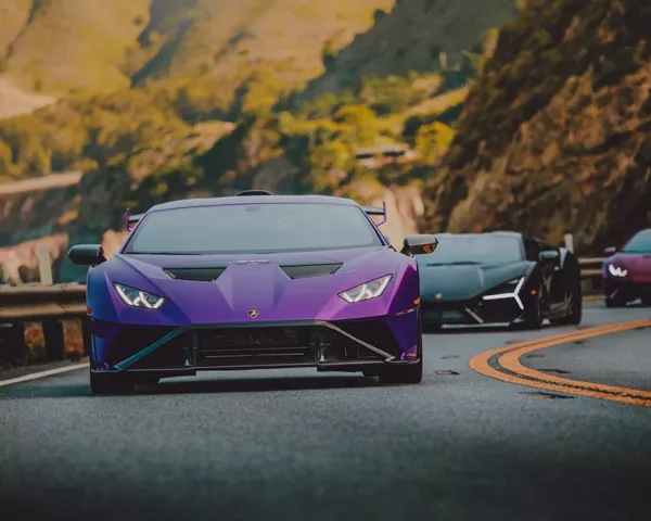 Photographie Lamborghini Party Photographie artistique d'un convoi de Lamborghini sur route sinueuse de montagne, avec une Huracán violette en premier plan suivie de plusieurs supercars italiennes