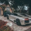 Photographie Lamborghini et McLaren Photographie artistique d'une Lamborghini argentée et d'une McLaren bleue devant un cottage rustique, contraste entre supercars modernes et architecture traditionnelle, tirage d'art automobile de luxe