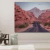 Photographie artistique de la route sinueuse traversant les formations rocheuses rouges de la Valley of Fire au Nevada, avec montagnes majestueuses au coucher du soleil