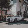 Photographie de voiture américaine Photographie artistique d'une Shelby Cobra 427 blanche avec bandes de course noires numéro 27 dans les rues pittoresques de Carmel-by-the-Sea, Californie