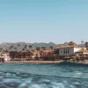Photographie de Marbella, Entre mer, plage et montagne Photographie artistique de Marbella depuis la mer, plage El Rosario, beach club NOSSO, maisons blanches andalouses, palmiers et montagnes Sierra Blanca sous ciel bleu
