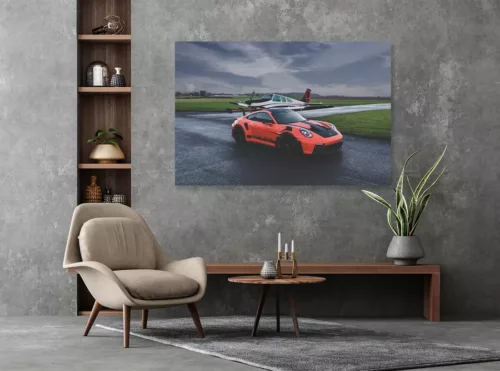 Porsche 911 GT3 RS orange sur piste d'aviation avec avion Beechcraft Bonanza en arrière-plan, photographie d'art automobile