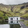 Photo de Seljavallalaug en Islande Photographie d'art de la piscine géothermique Seljavallalaug en Islande, eau turquoise entourée de montagnes volcaniques, paysage nordique sauvage