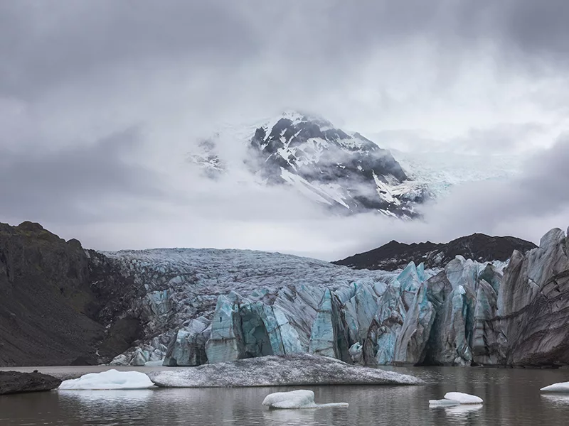 Photographie d'art du glacier Svinafellsjökull en Islande, teintes bleu turquoise et montagnes brumeuses,
