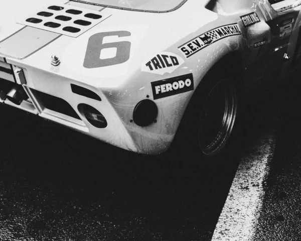 Photographie noir et blanc de l'arrière d'une Ford GT40 de course numéro 6 avec sponsors Ferodo et Koni, sur piste mouillée