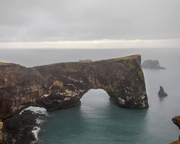 Photo déco murale de l'arche naturelle de Dyrhólaey en Islande montrant la falaise noire et l'océan sous un ciel dramatique, parfaite pour décoration intérieure nordique
