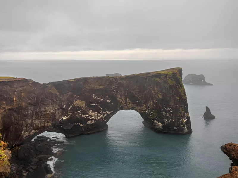 Photo déco murale de l'arche naturelle de Dyrhólaey en Islande montrant la falaise noire et l'océan sous un ciel dramatique, parfaite pour décoration intérieure nordique
