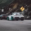 GT3rs et Bugatti Photo déco murale de Porsche GT3 RS blanche avec jantes turquoise et Bugatti Chiron noire sur route de canyon, parfaite pour décoration intérieure automobile de luxe