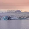 Photographie Islande Glacier Sunset Photographie déco murale du glacier Jökulsárlón en Islande montrant des icebergs bleu azur flottant sur le lagon glaciaire sous un ciel crépusculaire rose, parfaite pour une décoration intérieure scandinave