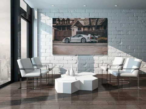 Tirage d'art Ferrari F40 grise affiché sur grande toile dans salon moderne minimaliste avec mur de briques blanches, mobilier contemporain et lumière naturelle