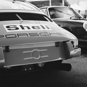 Voitures anciennes en tenue de exposition, montre l’arrière d’un Porsche classique avec logo Shell, décor automobile élégant. Décoration intérieure thème automobile.