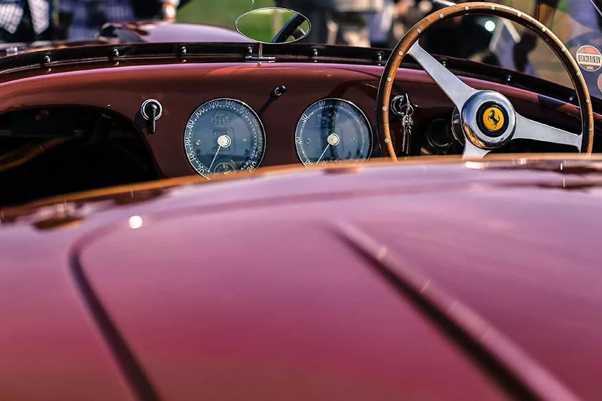 Tableau de bord d'une voiture de collection rouge bordeaux avec volant en bois et compteurs analogiques visibles. Tableau de bord d'une voiture de collection rouge bordeaux avec volant en bois et compteurs analogiques visibles.