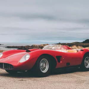 Voiture de sport classique rouge cabriolet, au design automobile Ferrari, sur une route près de la côte avec vue sur la mer.