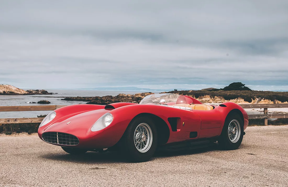 Voiture de sport classique rouge cabriolet, au design automobile Ferrari, sur une route près de la côte avec vue sur la mer.