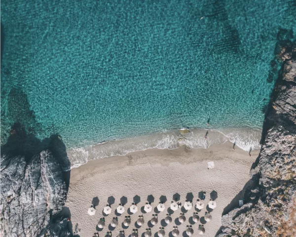 Photographie aérienne drone crique secrète Platanias Crète – eaux turquoise cristallines et parasols de plage vus du ciel