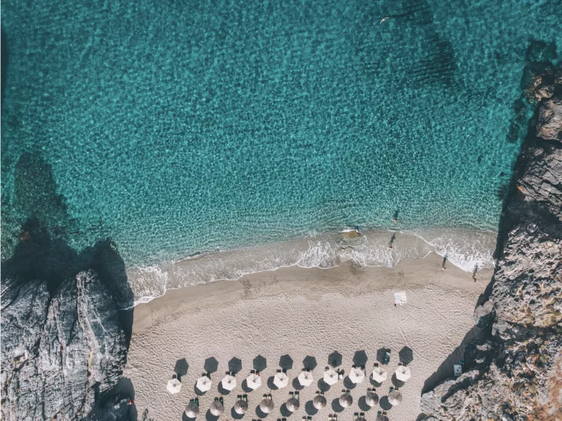 Photographie aérienne drone crique secrète Platanias Crète – eaux turquoise cristallines et parasols de plage vus du ciel