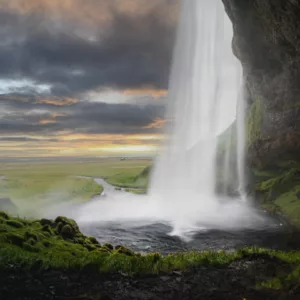 Cascade près d’un littoral verdoyant au soleil couchant, paysage islandais majestueux pour photographie paysages islande conseils