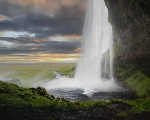Cascade près d’un littoral verdoyant au soleil couchant, paysage islandais majestueux pour photographie paysages islande conseils