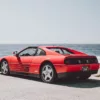 Ferrari 348 TS rouge garée face à l’océan sur la 17-Mile Drive à Pebble Beach, Californie, vue arrière trois quarts