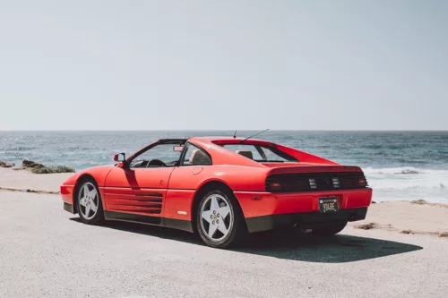 Ferrari 348 TS rouge garée face à l’océan sur la 17-Mile Drive à Pebble Beach, Californie, vue arrière trois quarts