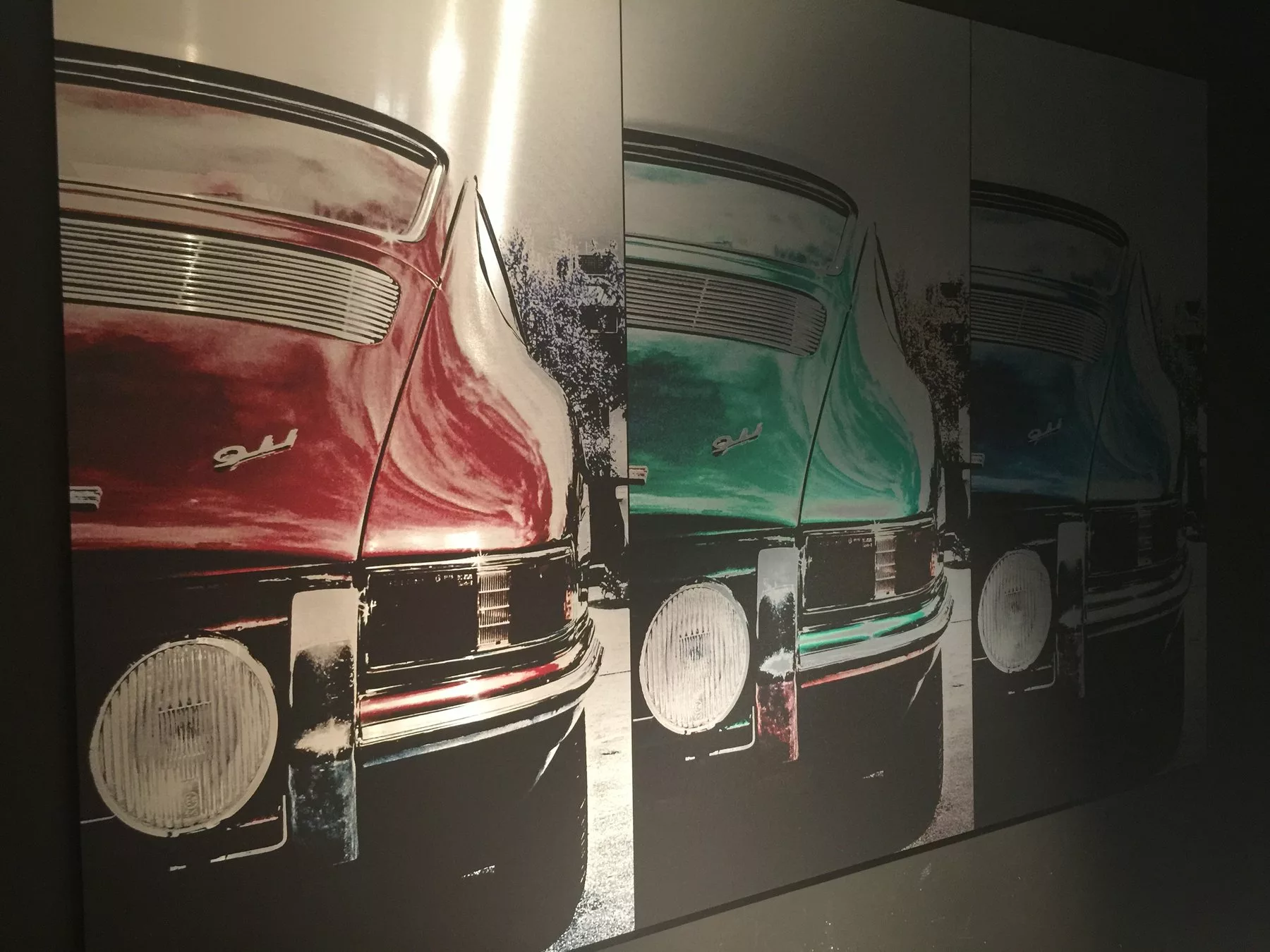 Gros plan sur un tirage sur aluminium brossé montrant l'arrière d'une Porsche 911 en panneaux rouge, vert et bleu