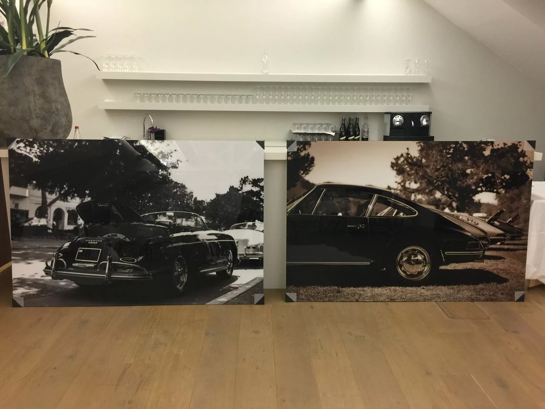 Deux tirages de 180×120 cm sous plexiglas, une Porsche 356 en noir et blanc et une rangée de Porsche 911 en sépia, déballés et posés contre un comptoir
