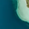 Photographie aérienne du lac de Kournas en Crète : eau bleu profond, hauts-fonds turquoise et petit bateau