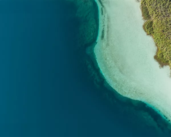 Photographie aérienne du lac de Kournas en Crète : eau bleu profond, hauts-fonds turquoise et petit bateau